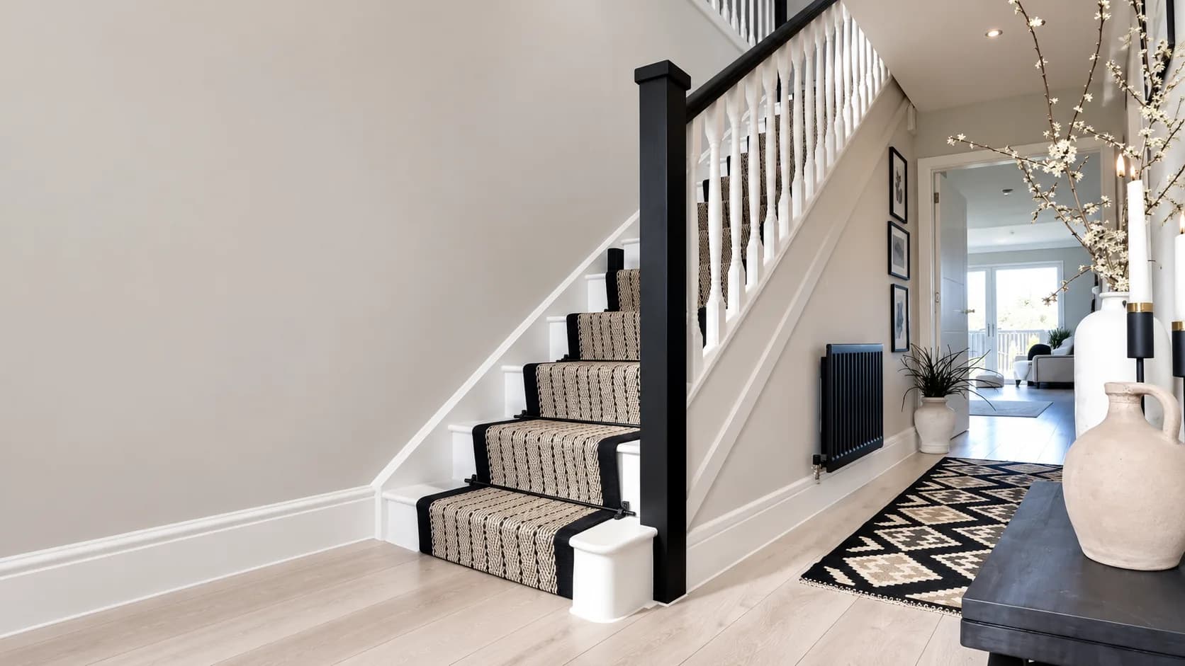 Illustrative London hallway with a black-and-white staircase, a striped stair runner and a black column radiator.